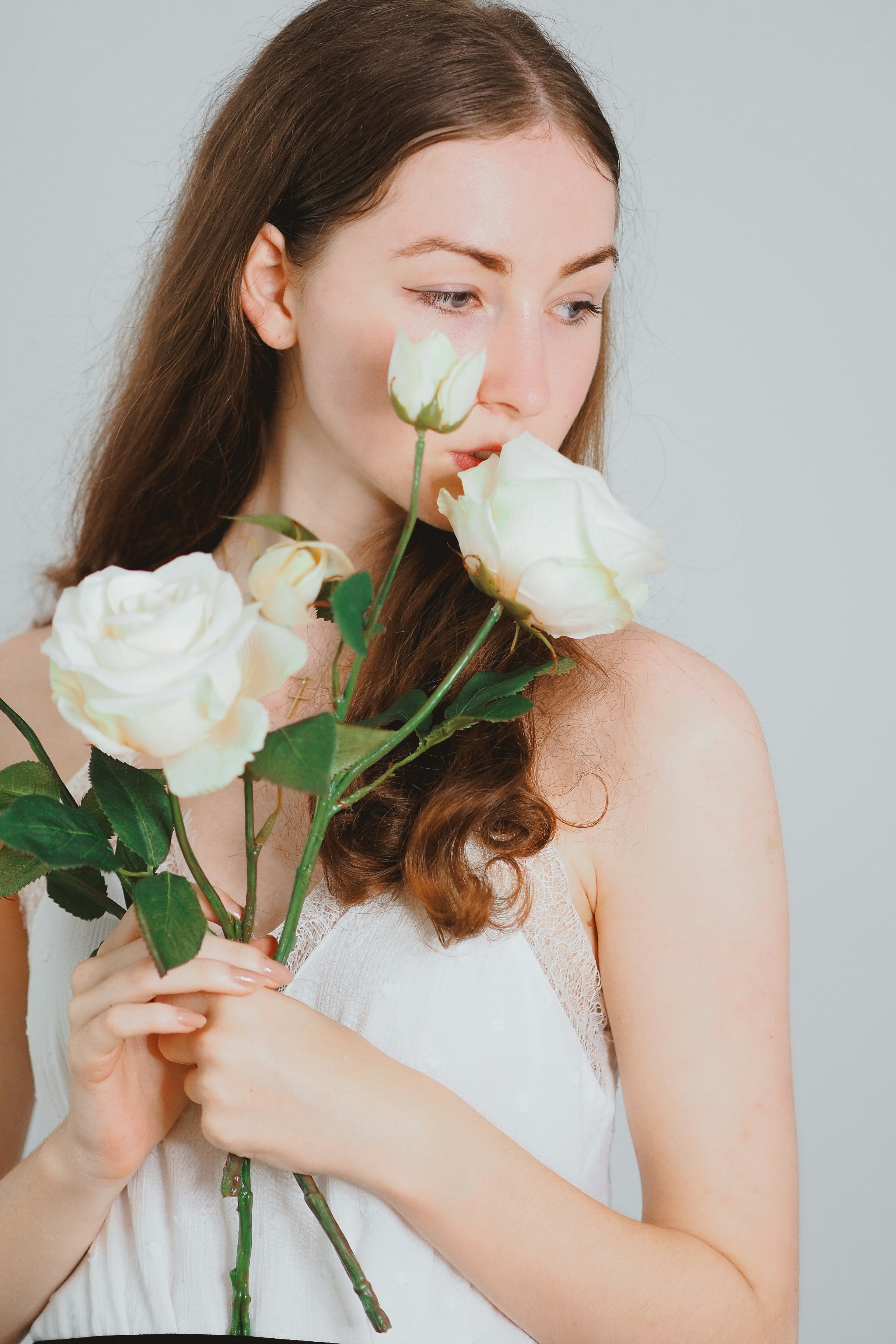 woman in white sleeveless dress holding white rose